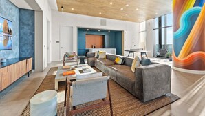 A modern living room with a large sectional sofa, a coffee table, and a vibrant abstract sculpture. - Modern Rainey St Oasis with Pool & Views (Austin)