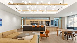 A modern hotel lobby with a central bar area, seating arrangements, and a large window providing natural light. - Modern Rainey St Oasis with Pool & Views (Austin)