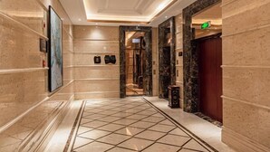 A hallway with marble walls, a tiled floor, and a framed artwork on the left. - Rezen Kingtown Hotel (Chongqing Liangping) (Chongqing)