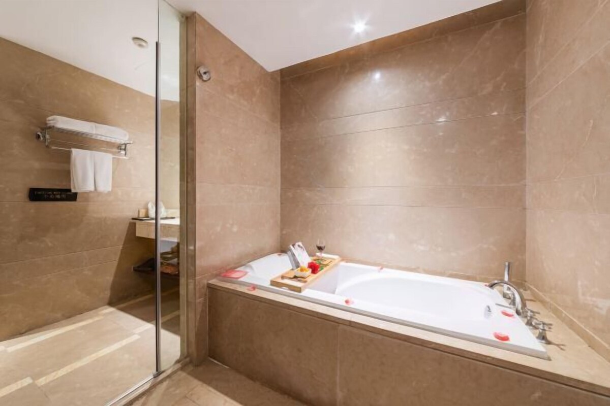 A modern bathroom with a large bathtub, a glass shower enclosure, and a towel rack.