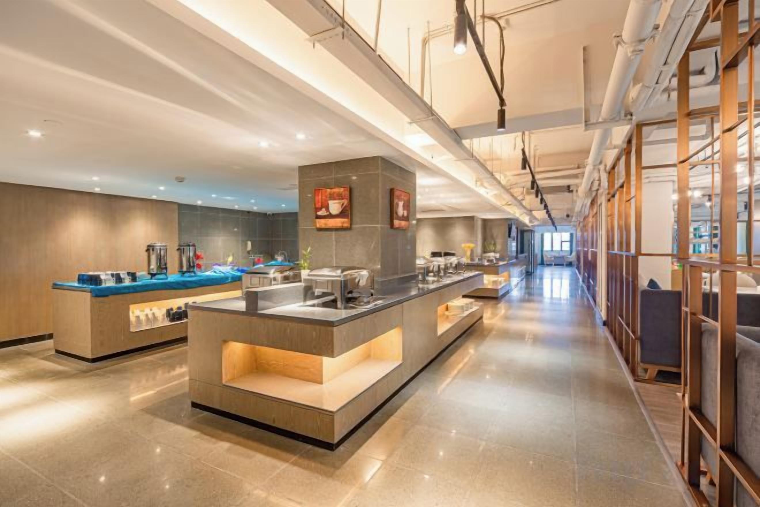 A modern hotel lobby with a central counter, seating areas, and a long corridor.
