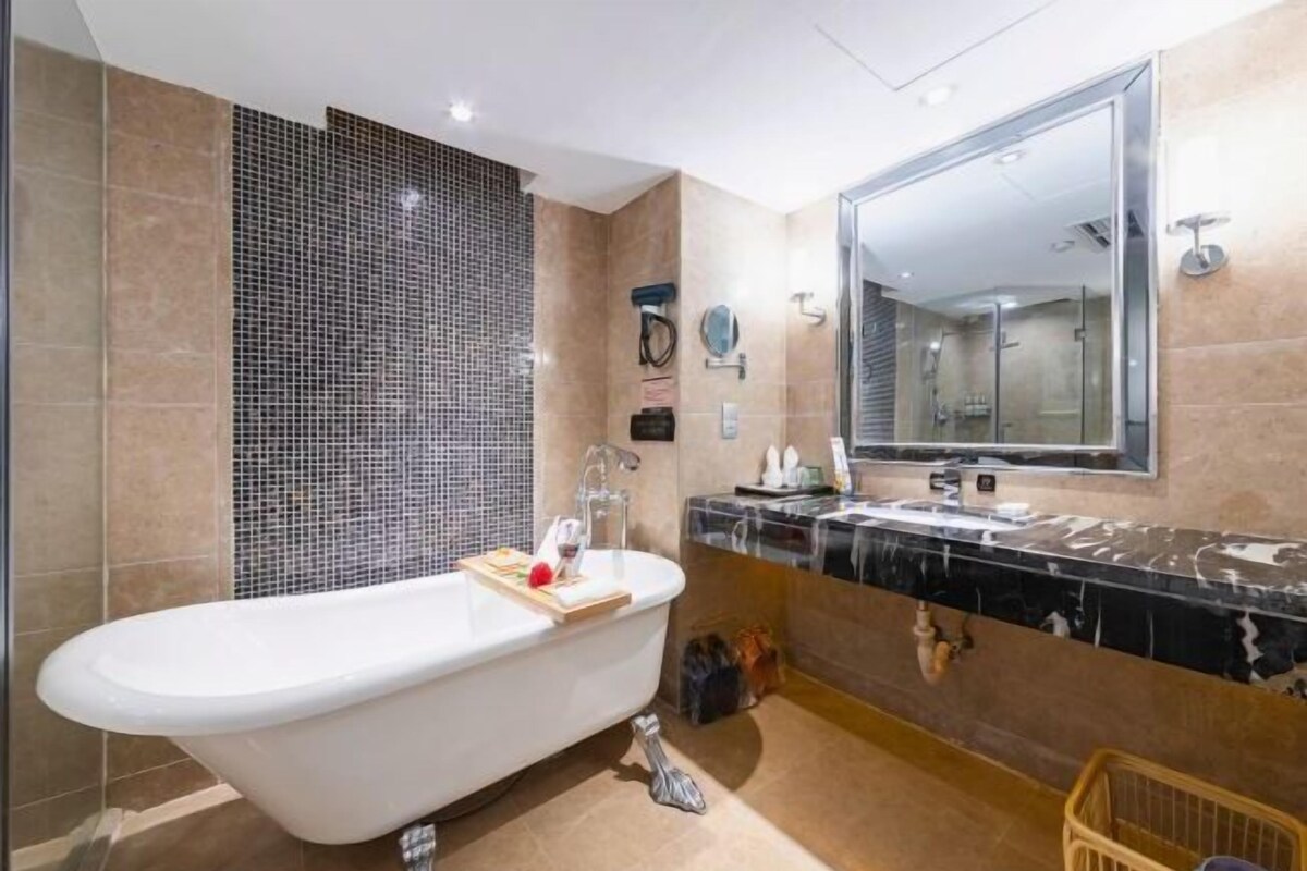 A modern bathroom with a freestanding bathtub, a large mirror, and a vanity with a sink and towel rack.