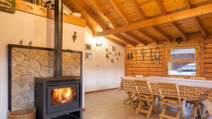 A rustic interior with a stone fireplace, wooden dining table, and chairs. - Apartments Bariloche - San Martin de los Andes Lodge (San Martín de los Andes)