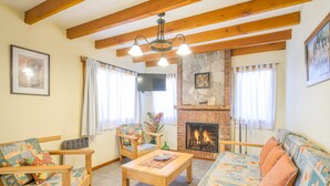 A living room with wooden furniture, a fireplace, and a stone accent wall. - Apartments Bariloche - San Martin de los Andes Lodge (San Martín de los Andes)