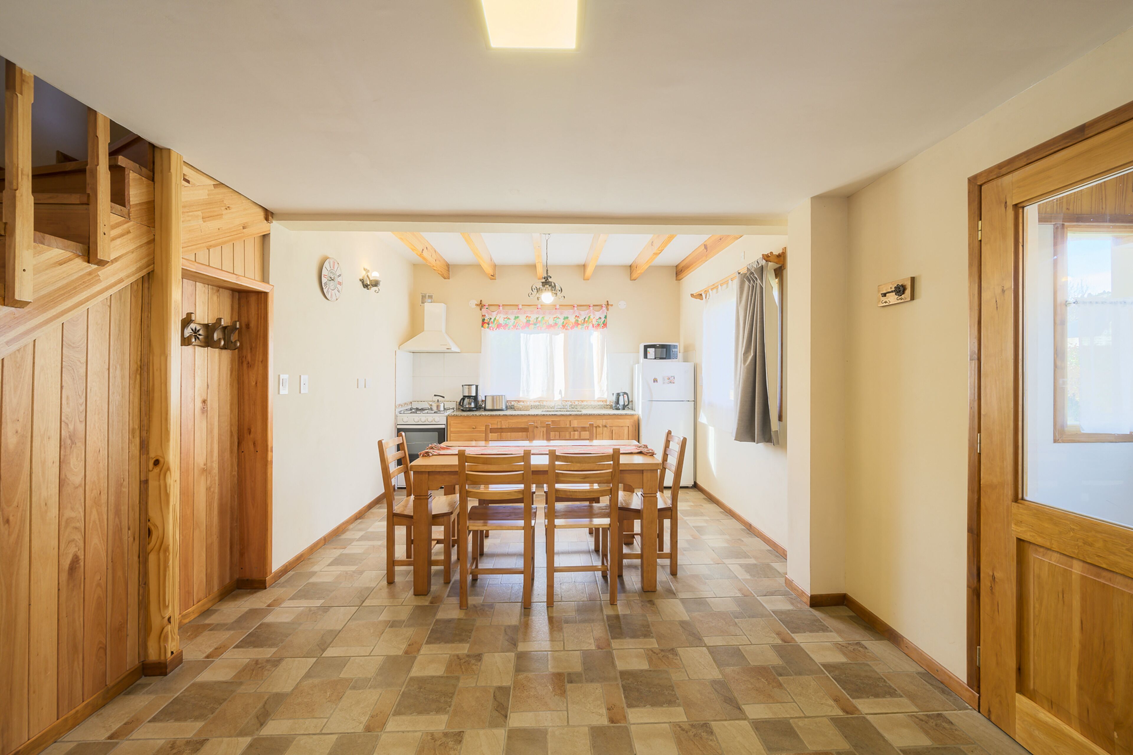 A spacious kitchen with a wooden dining table and chairs, a built-in oven, and a refrigerator.