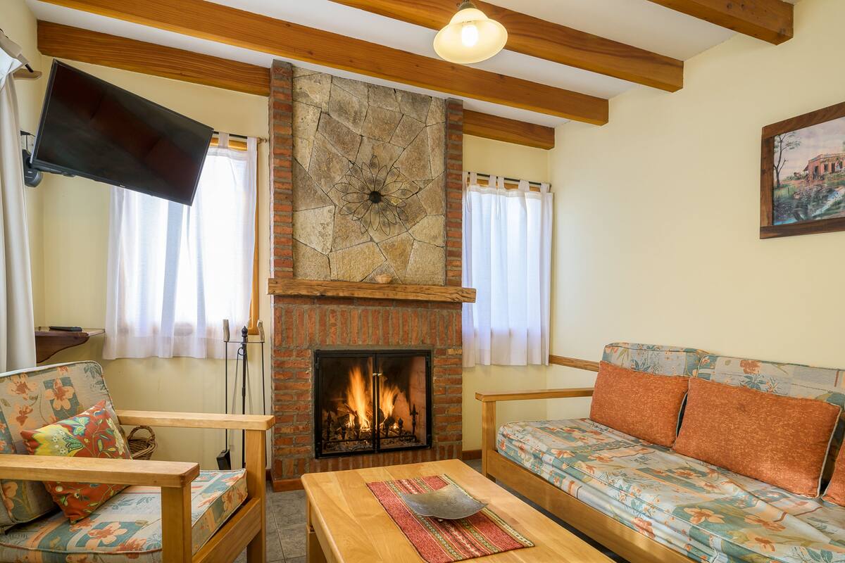 Ein Wohnzimmer mit Kamin, Holzmöbeln und einem an der Wand befestigten Flachbildfernseher.