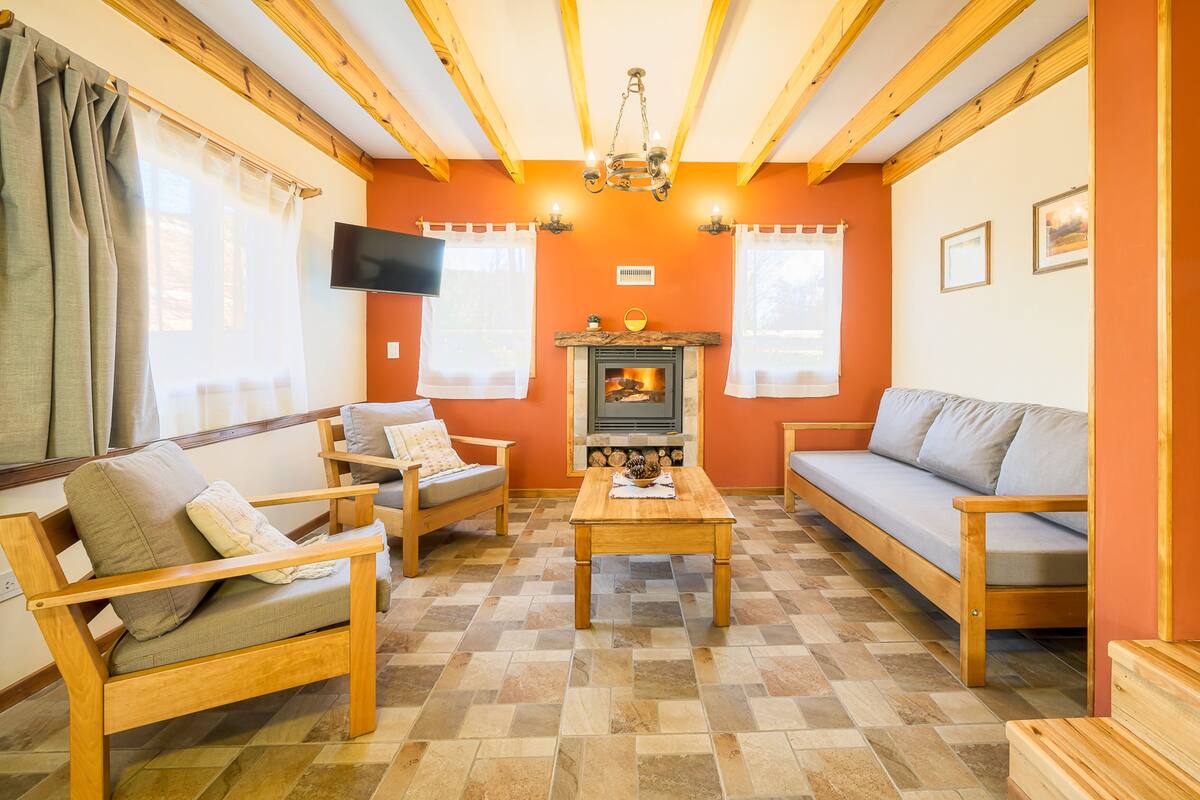 Ein gemütliches Wohnzimmer mit Holzmöbeln, einem Kamin und einem Fernseher an der Wand.