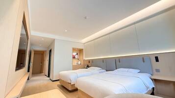 A modern hotel room with two beds, a large mirror, and built-in cabinets.