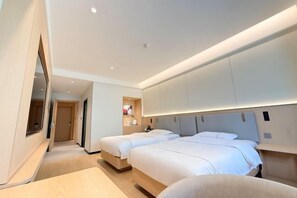 Une chambre d’hôtel moderne avec deux lits, un grand miroir et des placards intégrés.