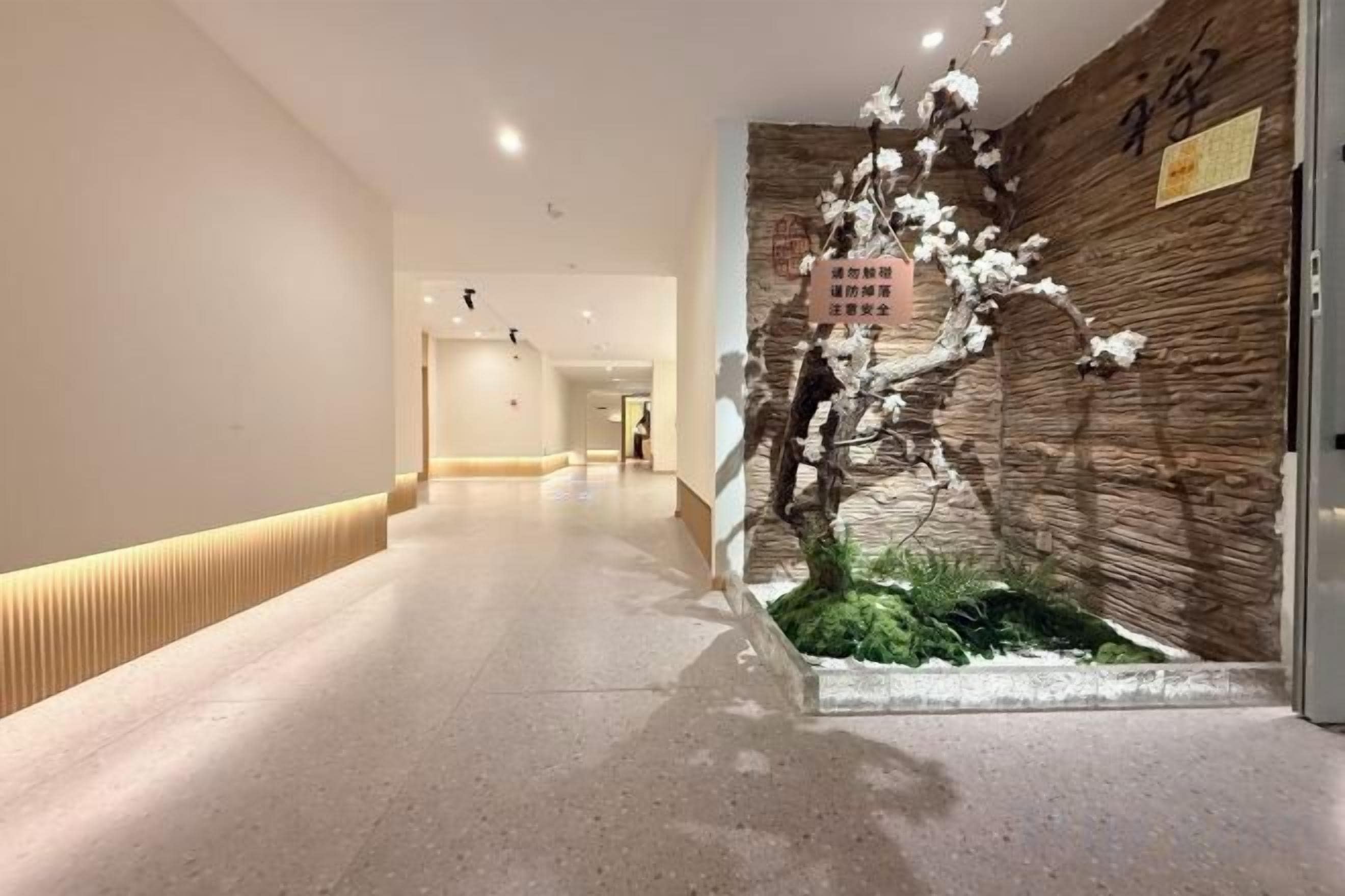 A hallway with a decorative tree sculpture, a wooden wall, and a sign.