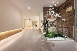Un pasillo con una escultura de árbol decorativa, un muro de madera y un cartel.