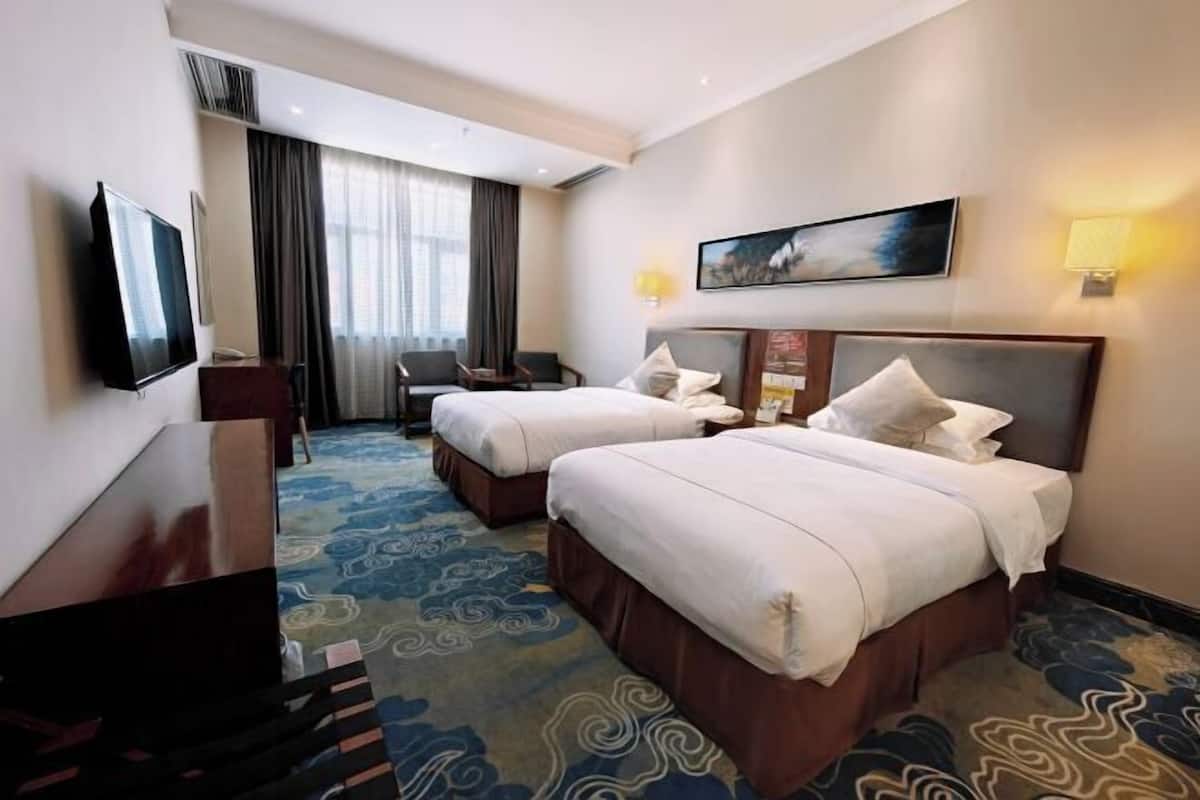 Een hotelkamer met twee bedden, een flatscreen-televisie, een bureau en een stoel.
