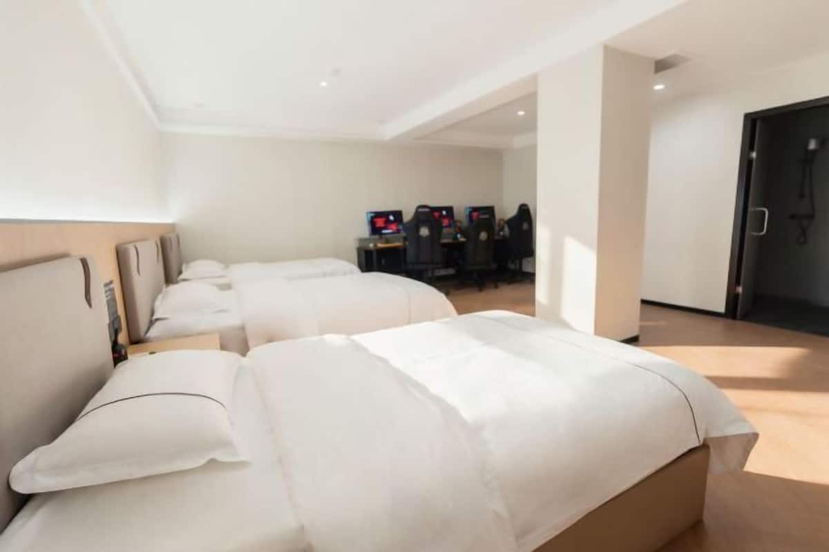 Een hotelkamer met twee bedden, een bureau met computers en een deur.