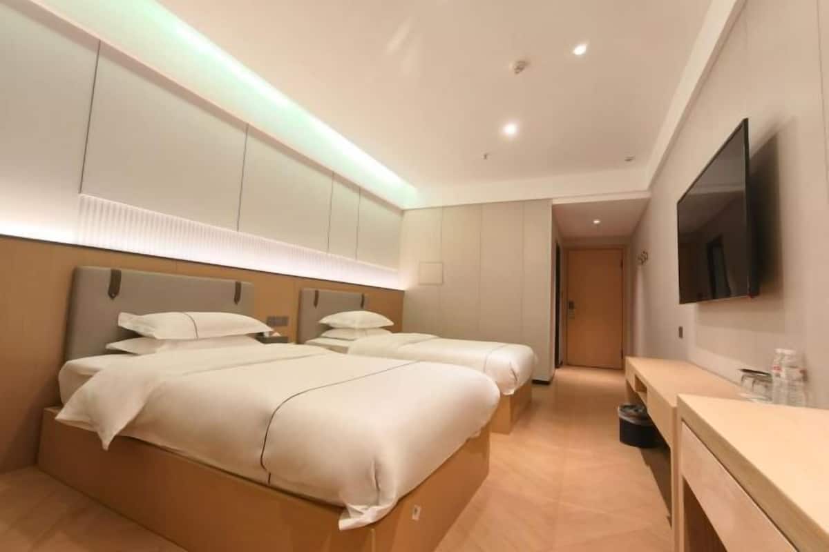 Een hotelkamer met twee bedden, een televisie, een bureau en een spiegel.