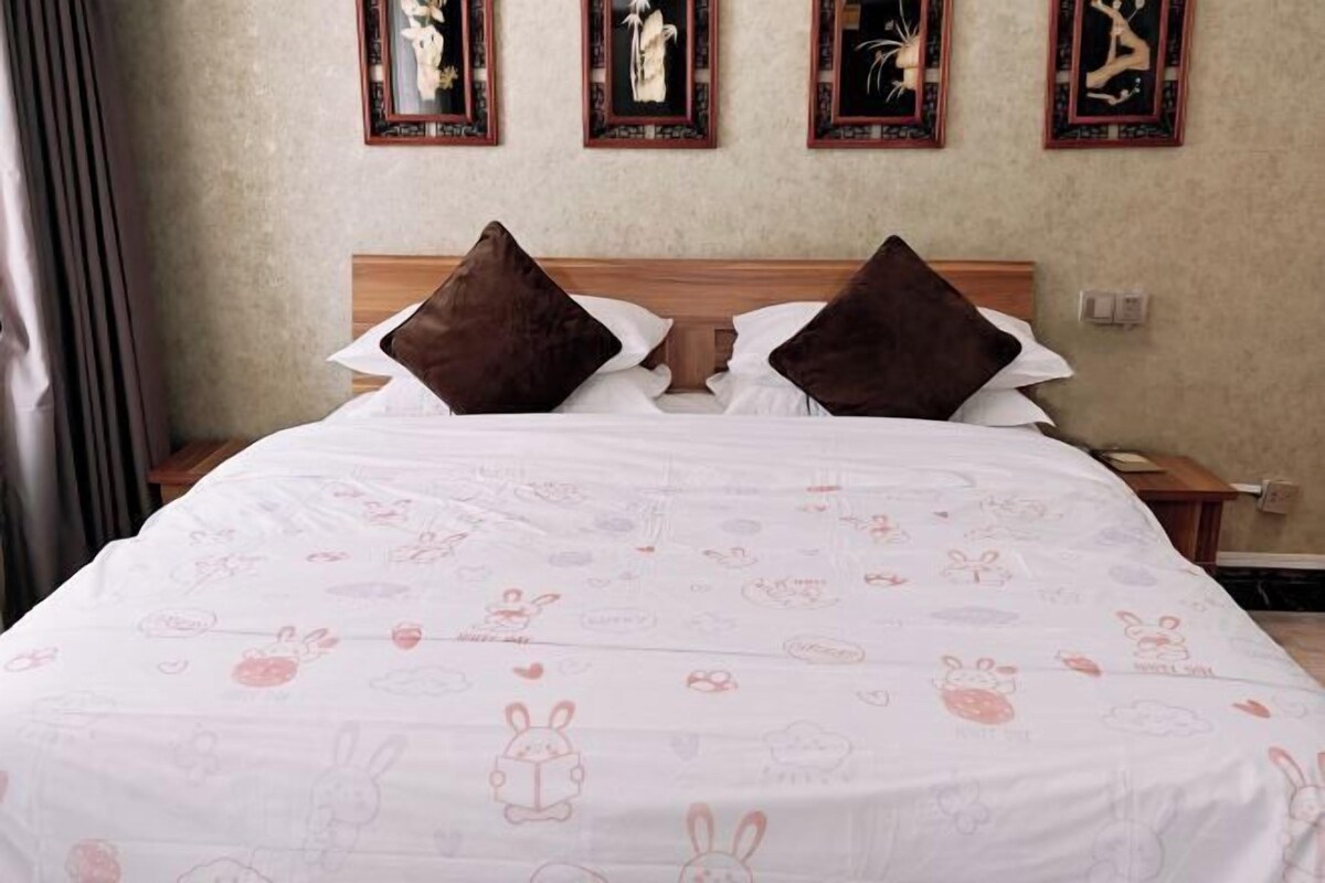 Een hotelkamer met een groot bed, twee nachtkastjes en een wand met ingelijste kunstwerken.