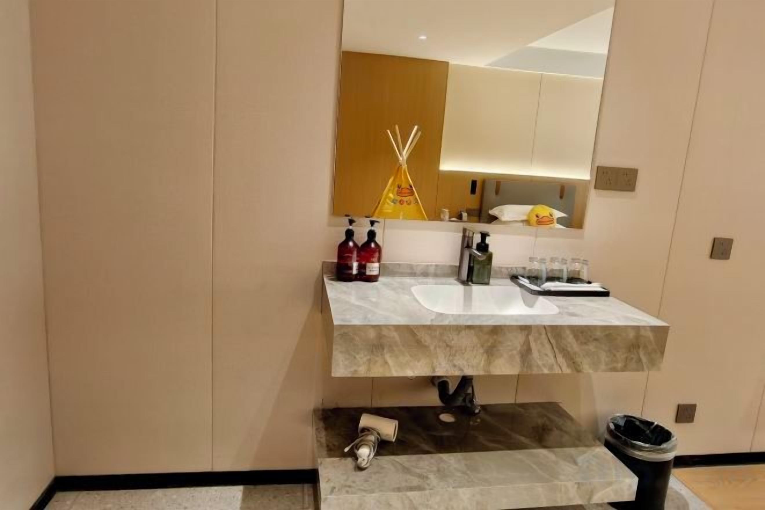 Un bagno moderno con un lavabo in marmo, uno specchio e un portasciugamani.