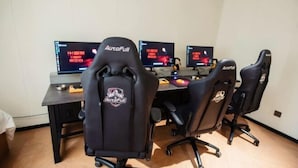Habitación con tres sillas de juego negras con la etiqueta 'AutoFull' y dos monitores de ordenador que muestran texto en rojo.