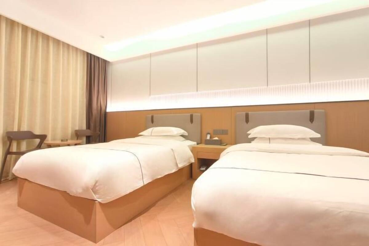 Een hotelkamer met twee bedden, een bureau, een stoel en een grote spiegel boven de bedden.