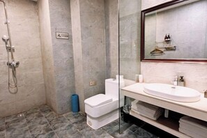 Een moderne badkamer met een glazen douchecabine, toilet en een wastafel met spiegel erboven.