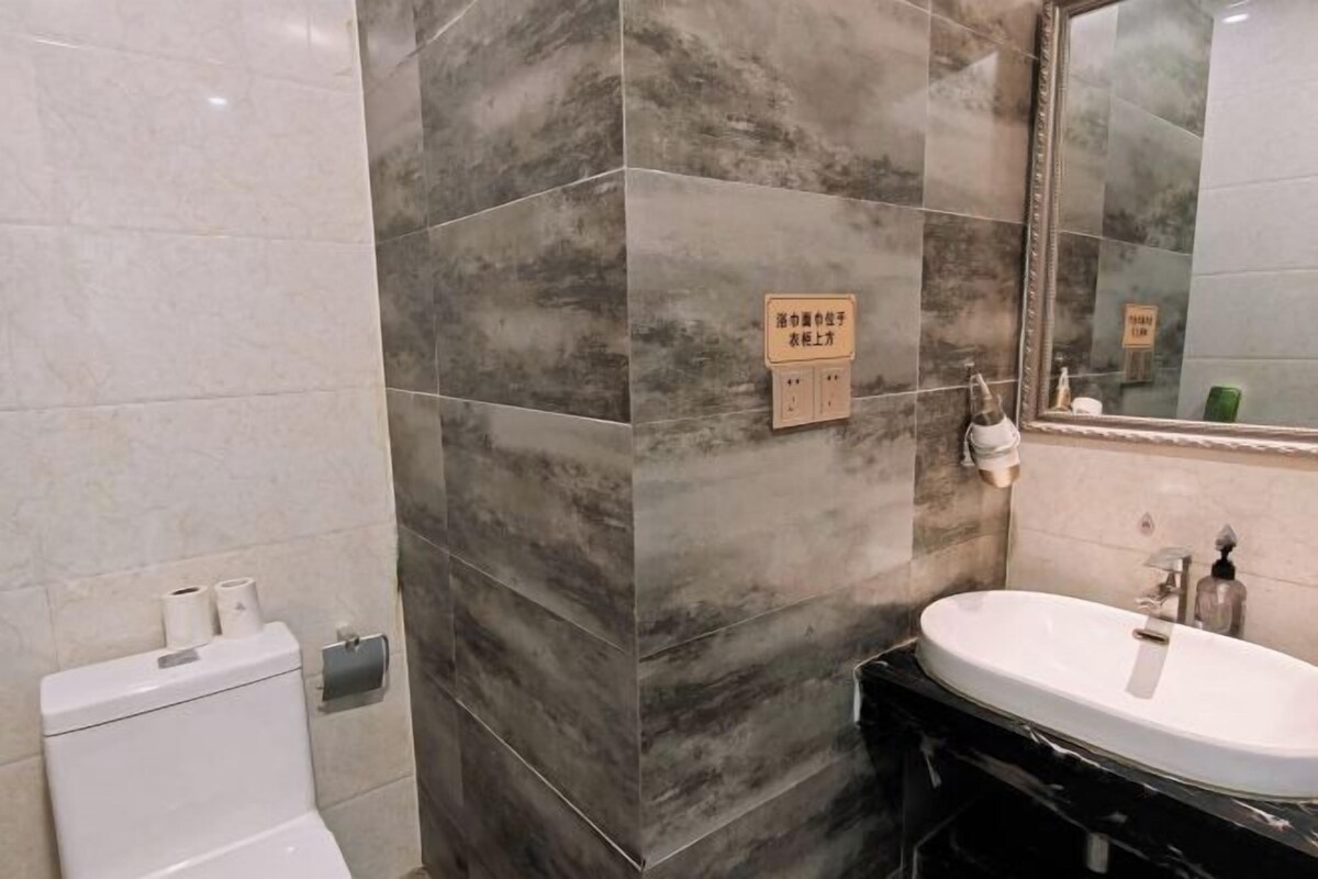 Een badkamer met toilet, wastafel en spiegel. Er liggen handdoeken en staat een zeepdispenser op de wastafel.