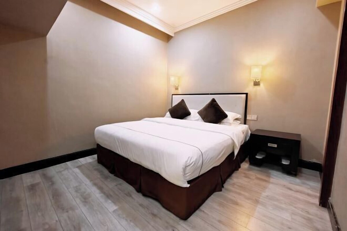 Een moderne slaapkamer met een groot bed, een nachtkastje en twee wandlampen.