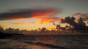 Une plage au coucher du soleil, où les vagues viennent doucement lécher le rivage.