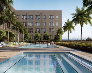 Un hotel moderno con zona de piscina, palmeras y vistas al océano.