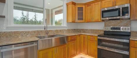 The full kitchen includes a stainless-steel farmhouse sink, dishwasher, microwave, and double oven.