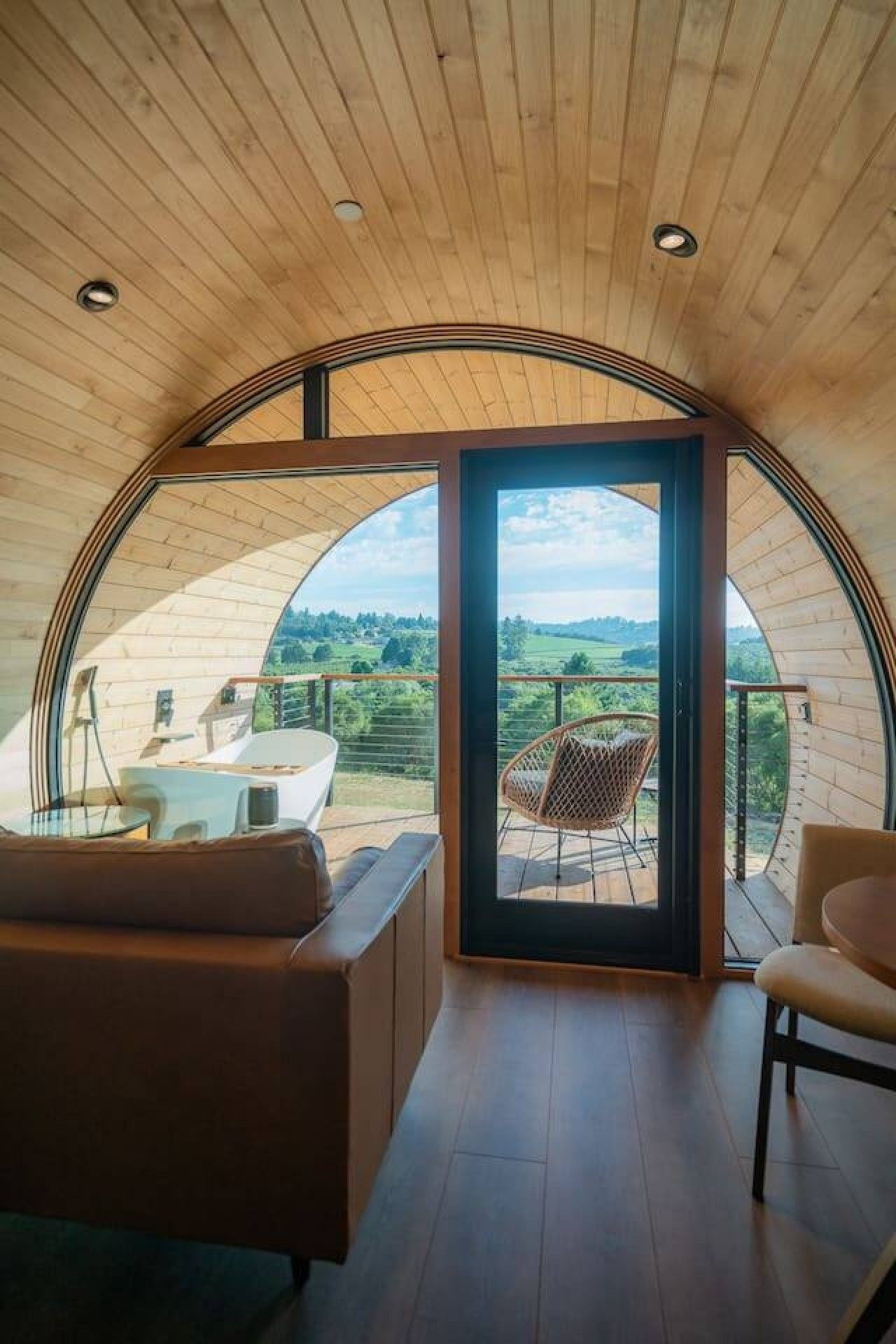 Een gezellig interieur met een gebogen houten plafond, een bank, een stoel en een tafel.