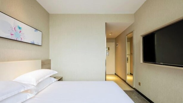 A hotel room with a bed, a flat-screen TV, and a painting on the wall. - HanTing Premium Hotel (Hangzhou Linping Intime City Subway Station) (Hangzhou)