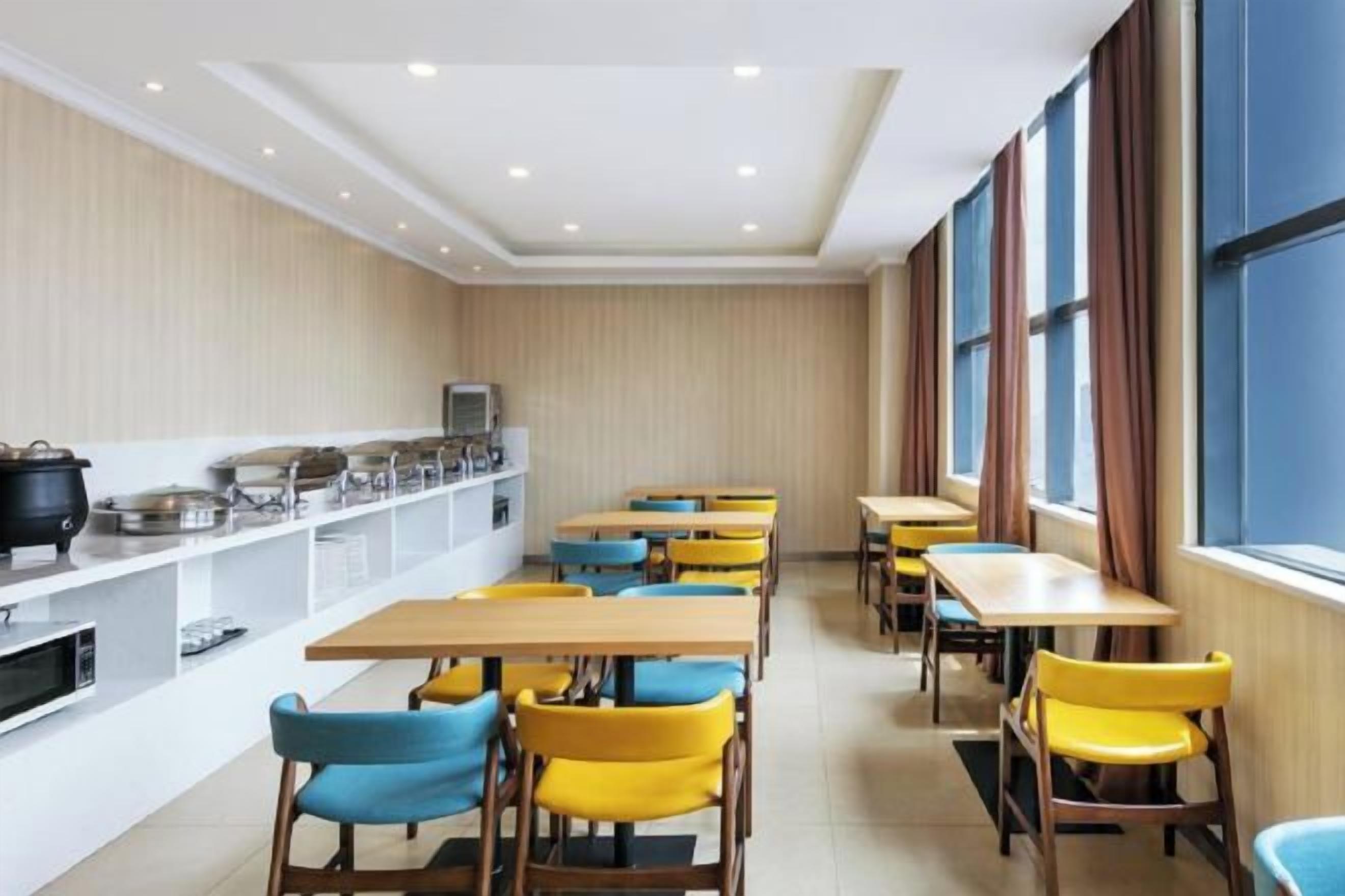 A dining area with tables and chairs, a buffet counter, and large windows.