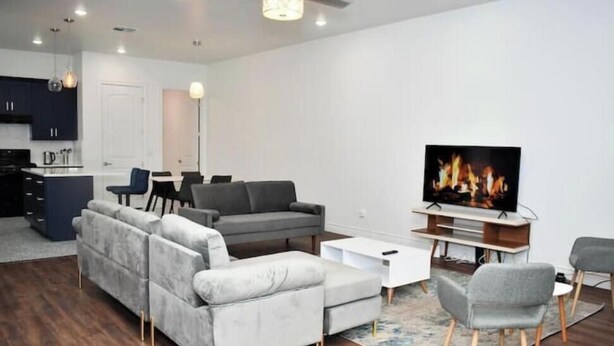 A modern living room with a grey sofa, a coffee table, and a flat-screen TV.