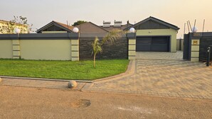 Una zona residenziale moderna con vialetto lastricato che conduce a un garage, un piccolo prato e un muro con cancello.