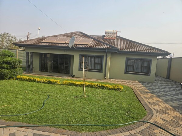 A two-story house with a tiled roof, a satellite dish, and a paved driveway.