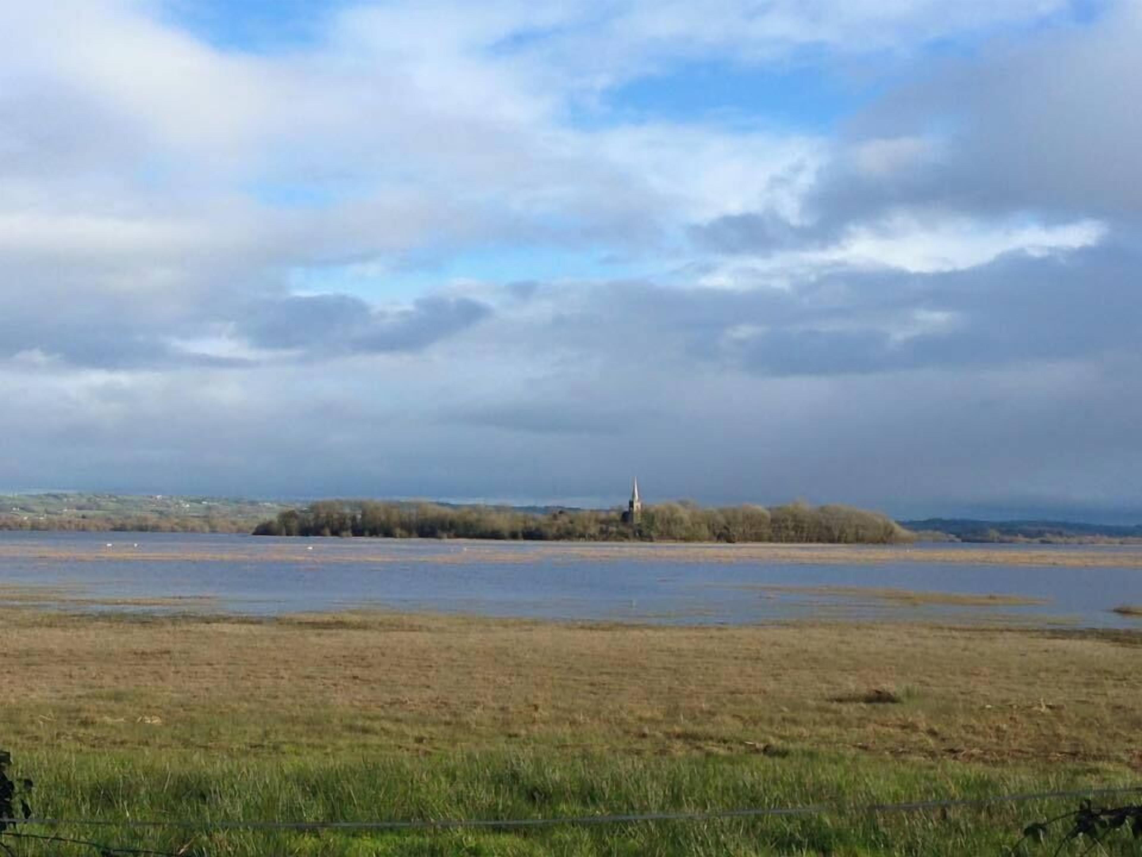 A wide-open field with a distant church on a hill.