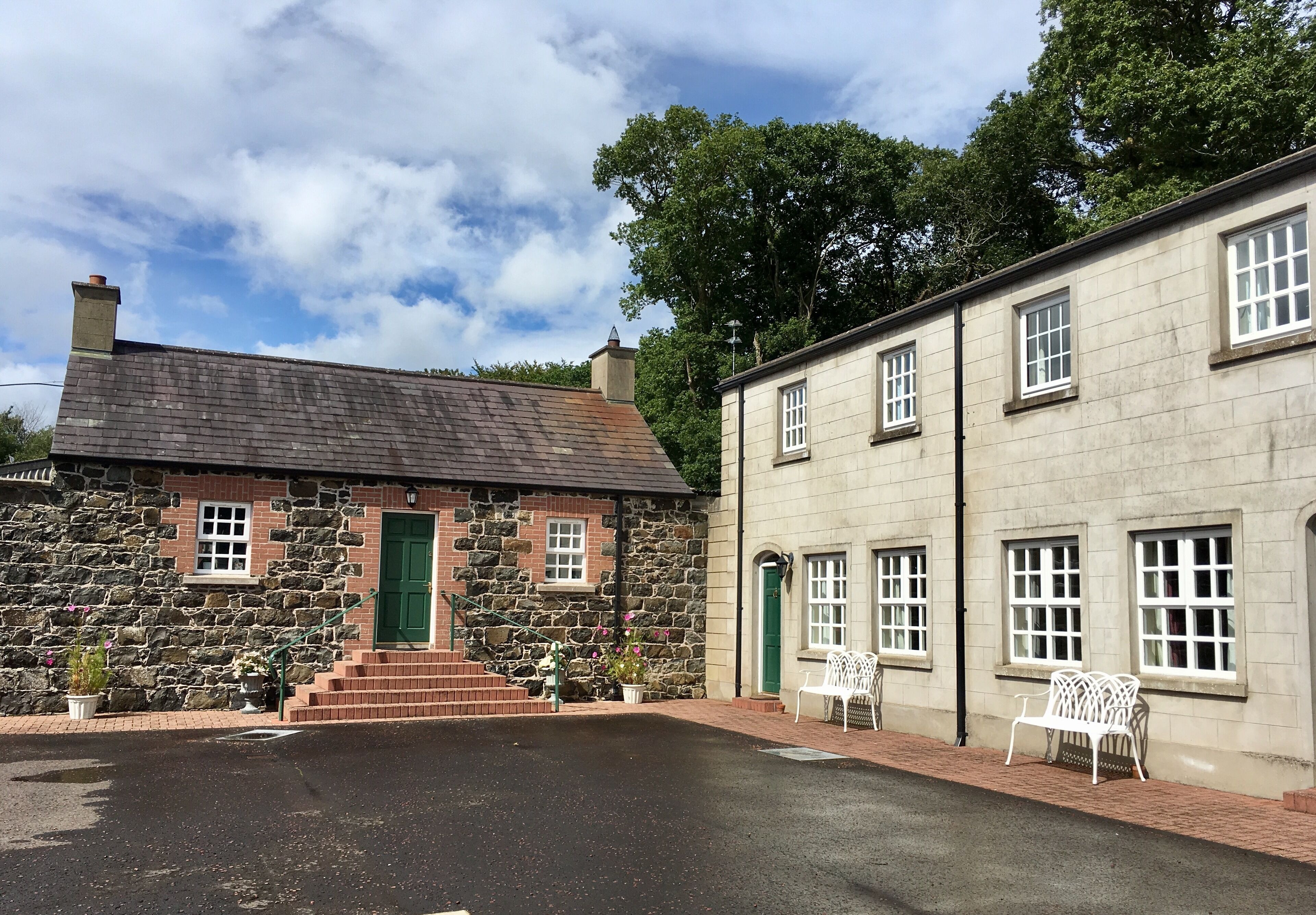 A stone building with a green door and steps leading to a porch.