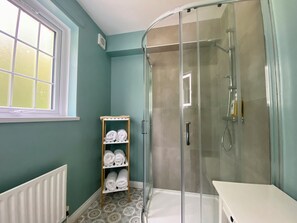 Een aparte badkuip en douche, een haardroger, handdoeken, zeep