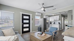 A modern living room with a wooden coffee table, a blue armchair, and a black door. - Charming Beach Retreat (St. Pete Beach)