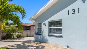 A residential building with the number 131, a window with a 'W' sign, and a paved driveway with shadows. - Charming Beach Retreat (St. Pete Beach)