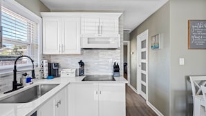 A modern kitchen with white cabinets, a built-in microwave, and a coffee maker. - Charming Beach Retreat (St. Pete Beach)