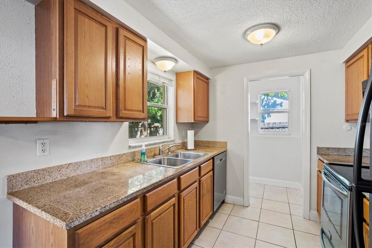 A kitchen with wooden cabinets, granite countertops, a dishwasher, and a refrigerator.