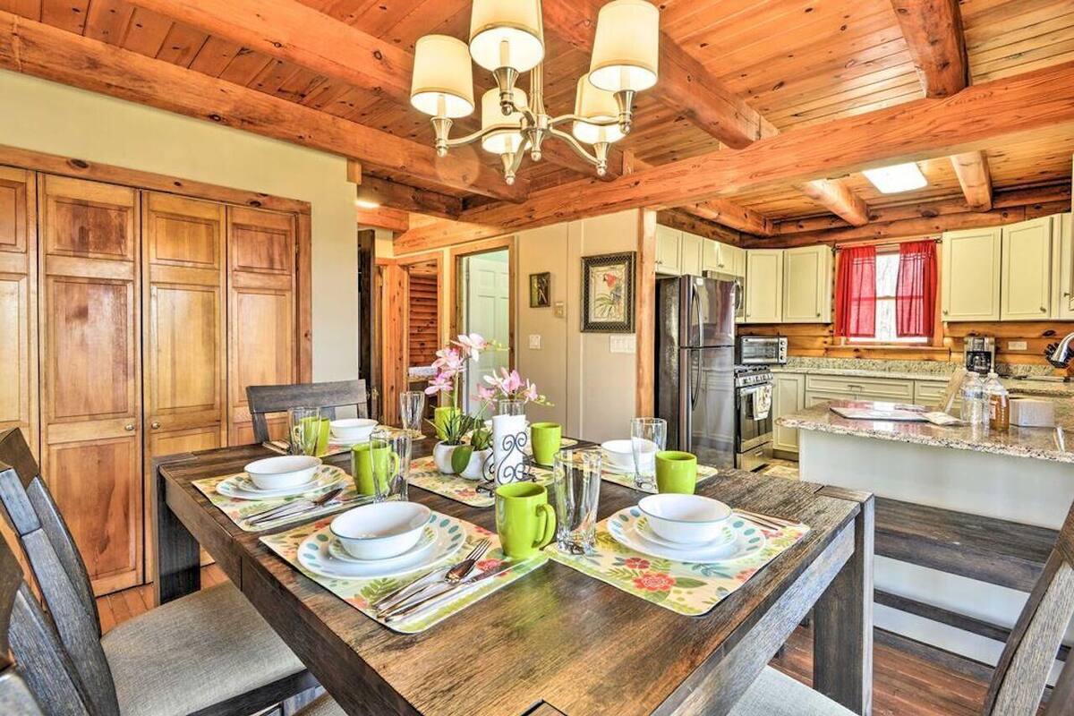 A wooden dining table set with plates, cups, and cutlery, surrounded by chairs.