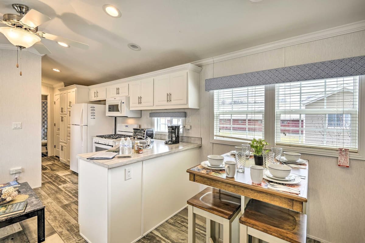 A modern kitchen with white cabinets, a central island, and a window with blinds.