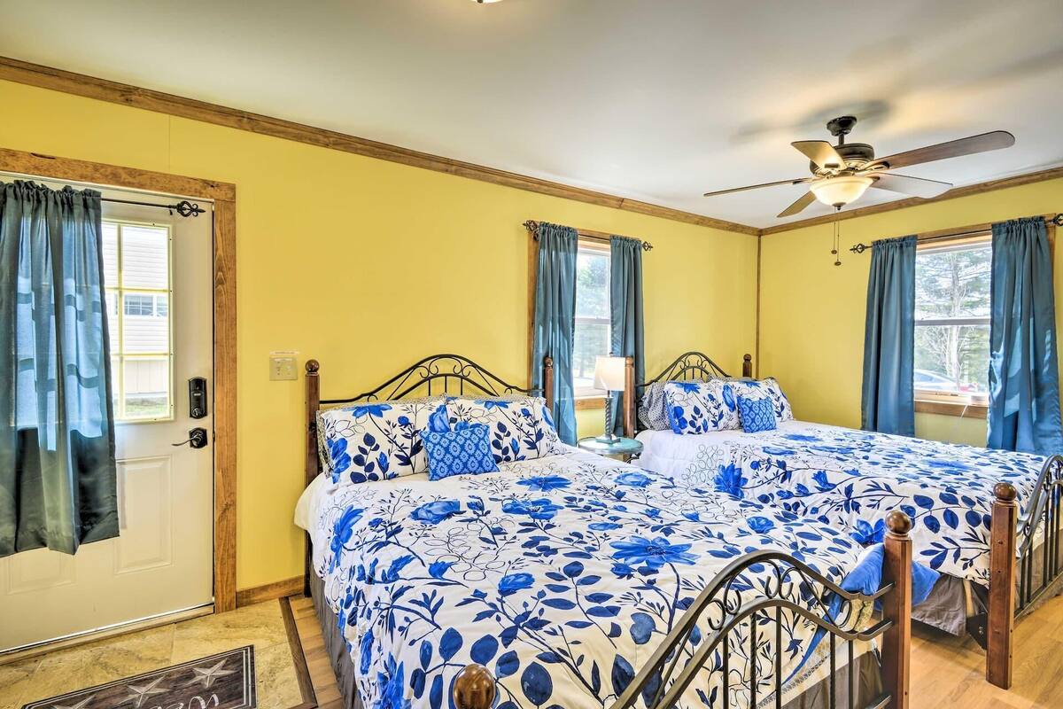 A bedroom with two beds, a ceiling fan, and a window with curtains.