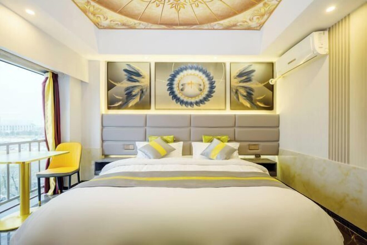 Une chambre d’hôtel dotée d’un grand lit, d’une chaise, d’un balcon avec vue et d’œuvres d’art décoratives sur les murs.