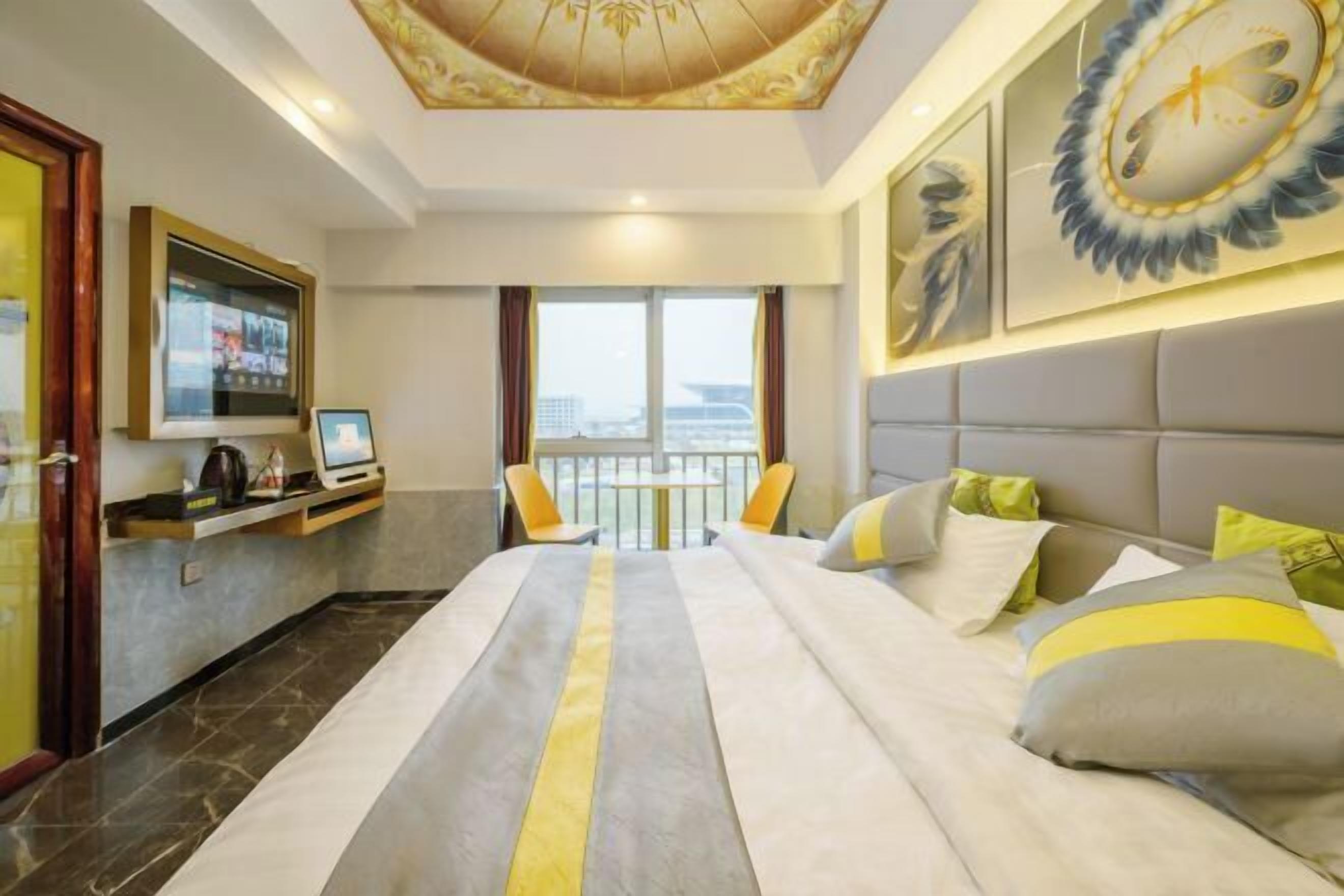 Habitación de hotel con cama, televisión, escritorio y balcón con vistas.