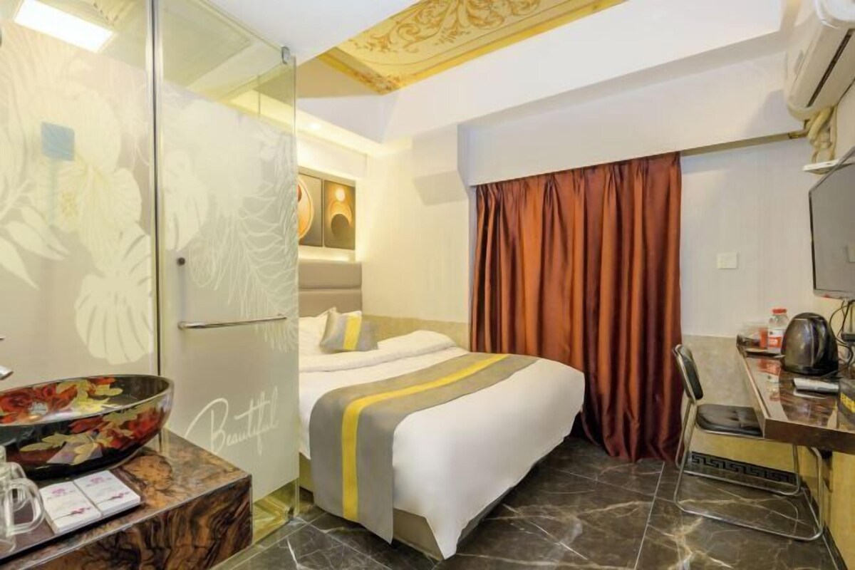 Une chambre d’hôtel comprenant un lit, un bureau avec une chaise, une douche en verre et un mur décoratif.