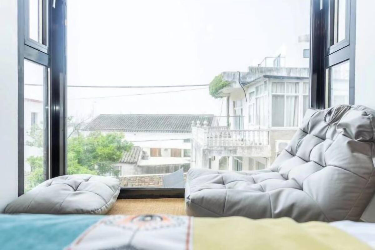 Une chambre avec un lit, une fenêtre et une vue sur des bâtiments traditionnels.