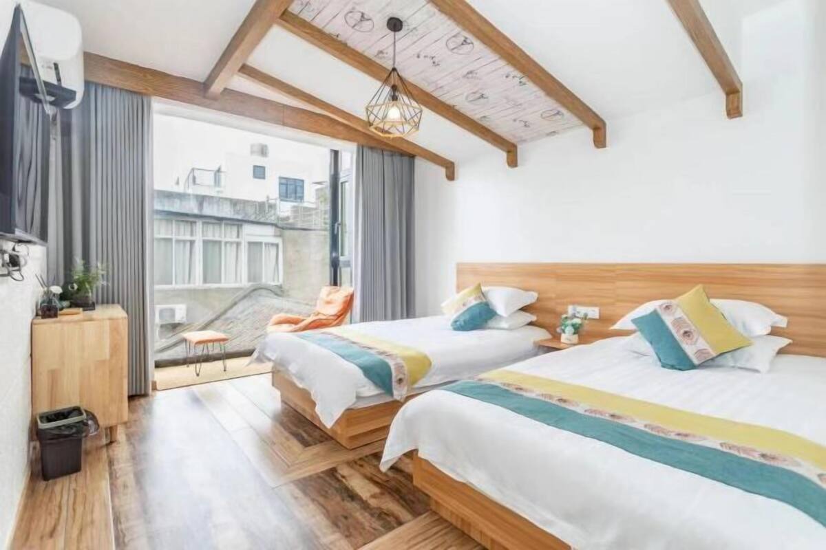 Une chambre d’hôtel avec deux lits, une tête de lit en bois, un petit bureau, une chaise et un balcon avec vue.