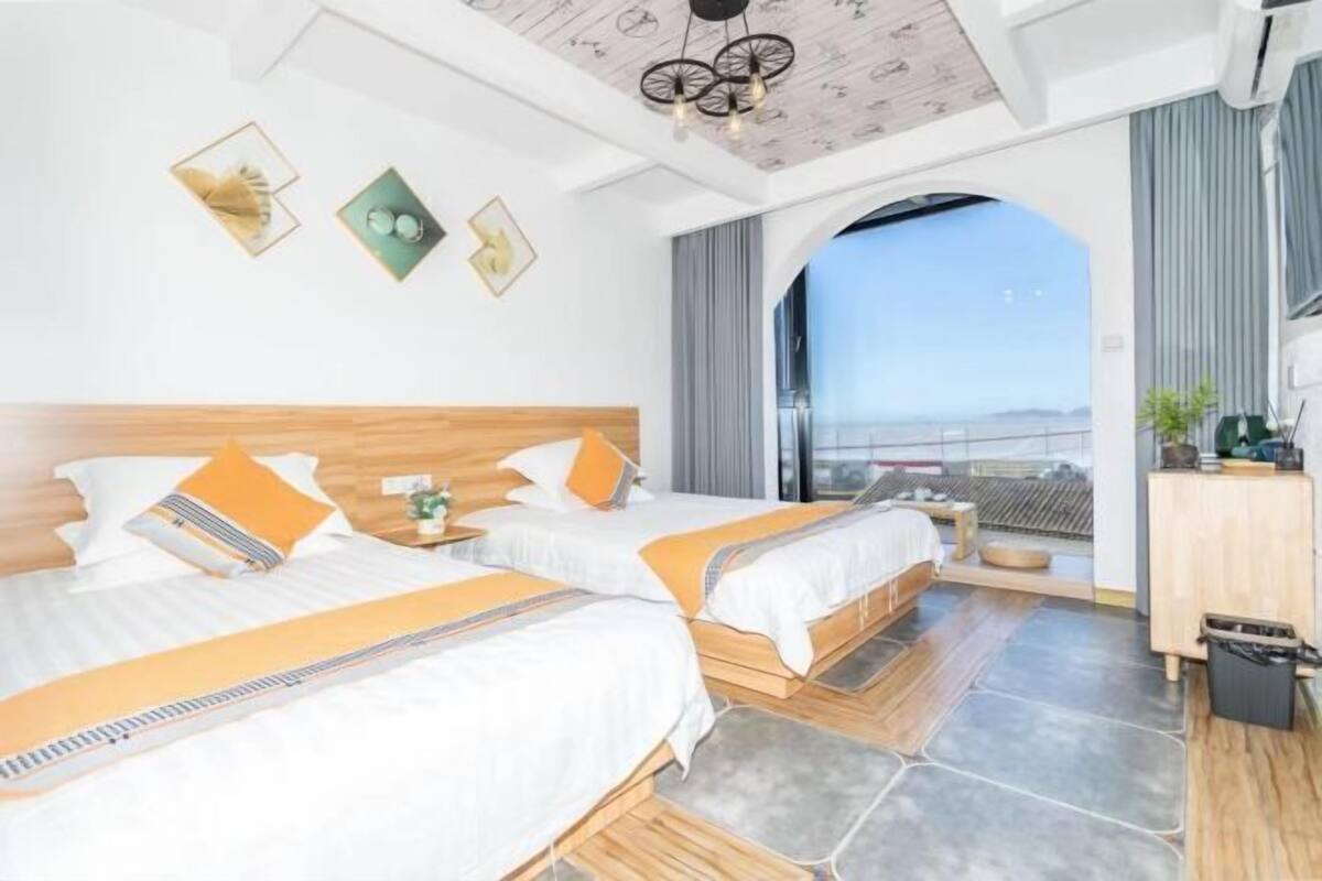 Une chambre d’hôtel avec deux lits, une vue à travers une fenêtre en arc de cercle et un plafond au design original.